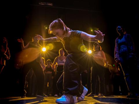 A person dances in the middle of a circle of other dancers. 